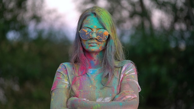 Portrait of boy standing being covered in coloured powder at holi festival.