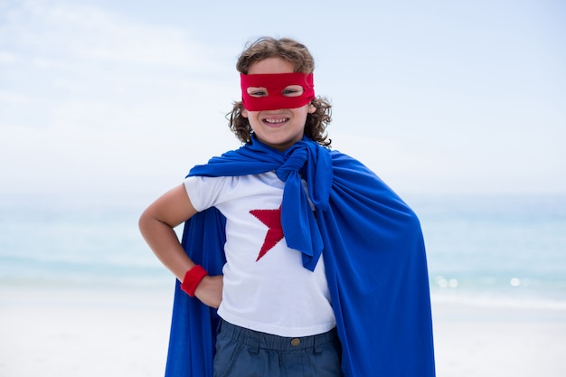 Portrait of boy in superhero costume at beach