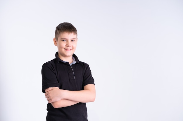 Portrait of boy teenager in black t-shirt looking at camera, smiling with positive feeling on his face on white background