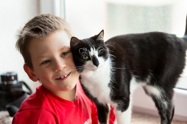 Portrait of a boy with a black and white cat. Friendship of a kitten and a child