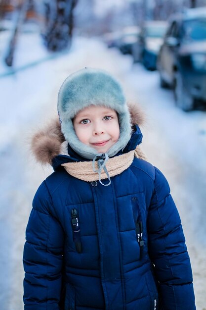 Portrait of a boy with large eyes a warm hat and jacket on a winter street