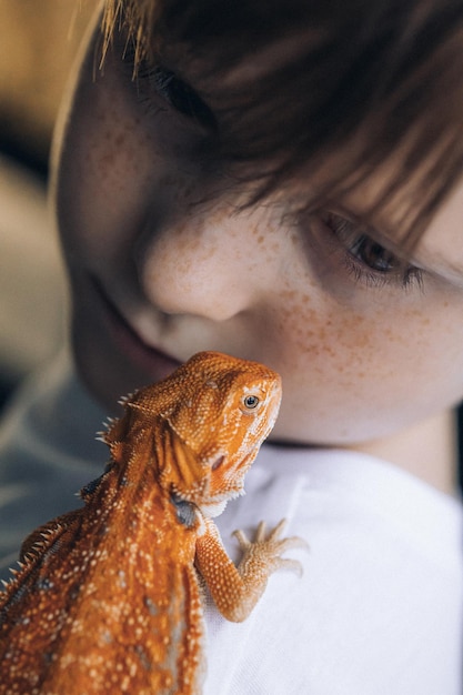 Portrait of boy with Red bearded Agama iguana Little child playing with reptile Selective focus