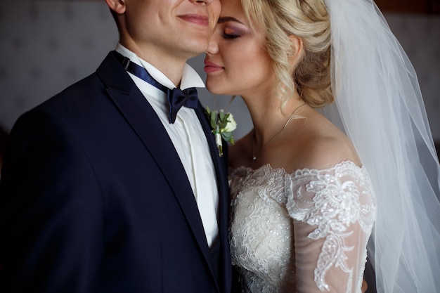 portrait of bride and groom close up. portrait of a loving  newlyweds . bride gently hugs and kisses the groom. wedding day. portrapt a happy wedding couple in love indoor