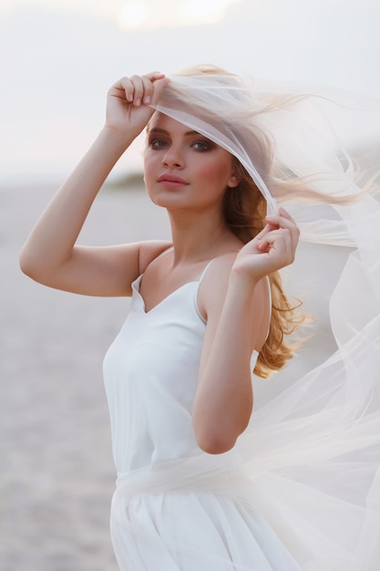 portrait of a bride near the ocean. model looks through a veil.