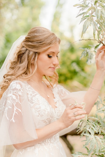 Portrait of a bride touching leaves on a tree