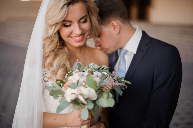 Portrait of a bridegroom kissing a blonde bride shulder