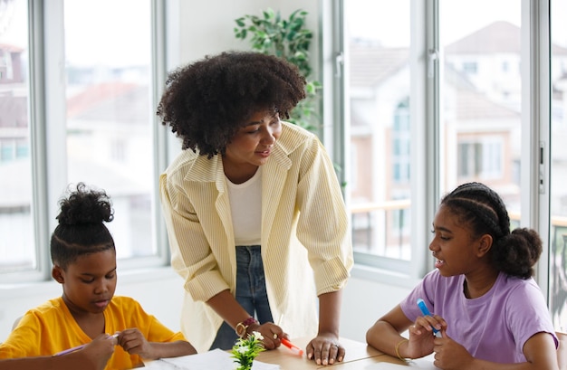 Portrait of a Brilliant Black Girl with Braces Writes in Exercise Notebook Smiles Junior Classroom with Diverse Group of Children Learning New Stuff