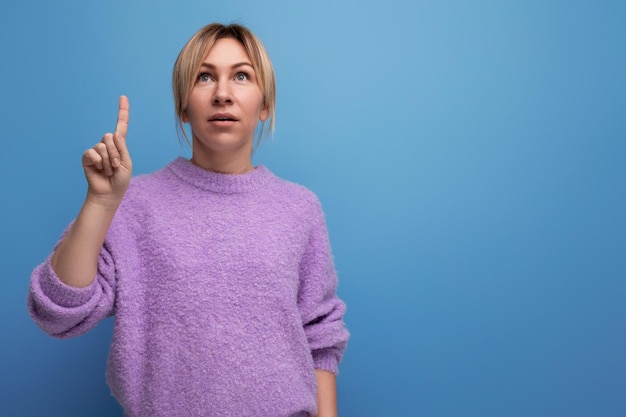 Portrait of a brilliant blonde young woman in a lilac sweater with a good thought on a bright