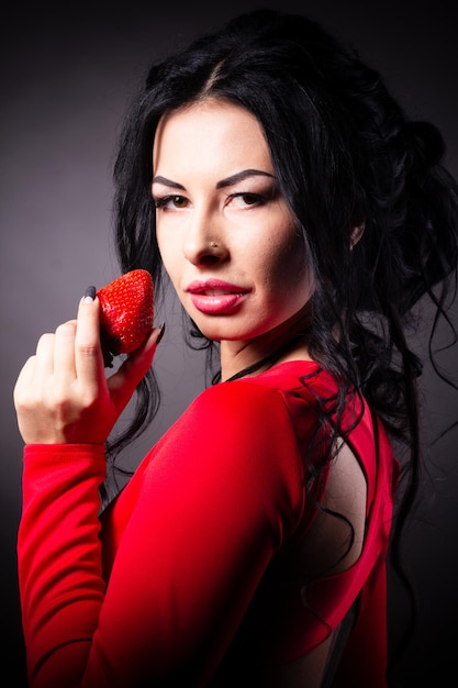 Portrait of a brunette beauty with honey dripping strawberry