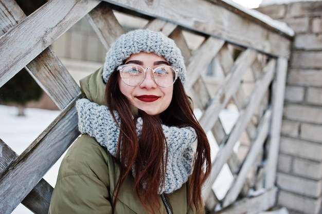 Portrait of brunette girl in gray scarf and hat glasses at cold weather