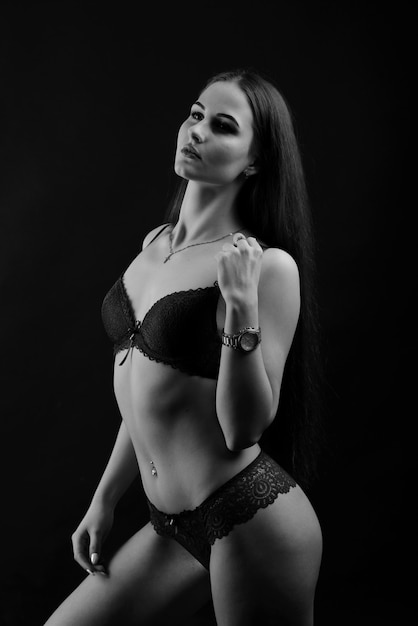 Portrait of brunette girl in underwear standing in the studio with black background.