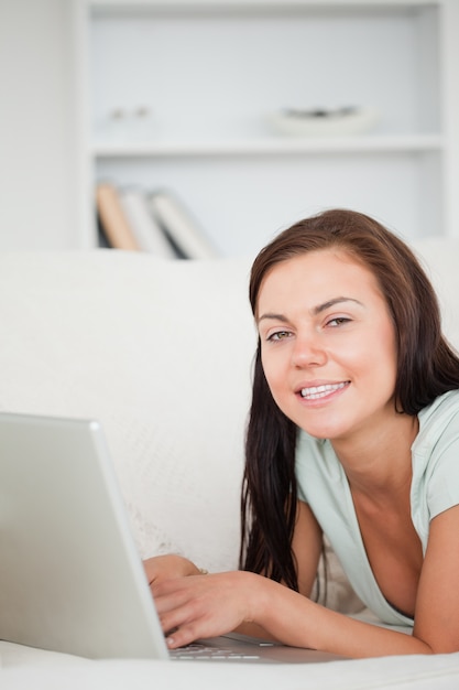 Portrait of a brunette on a sofa using a laptop