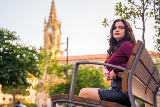 Portrait of a brunette woman in a leather skirt sitting in the city lifestyle fashion pose