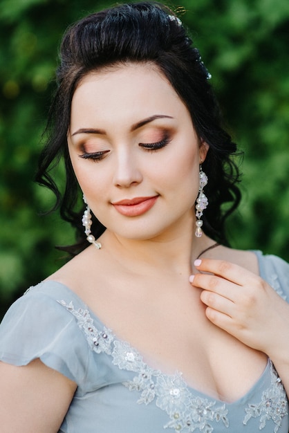 Portrait of a brunette woman in a lilac spring garden before the wedding ceremony