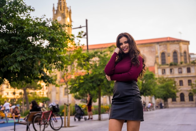 Portrait of a brunette woman with a leather skirt next to a church visiting the city lifestyle