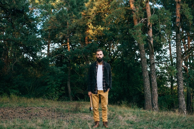 Portrait brutal bearded and moustached woodcutter hipster Gypsy man in the forest with axx9