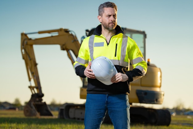 Portrait of builder in a construction site Builder with excavator ready to build new house Construction builder wear building uniform on excavation truck digging builder construction