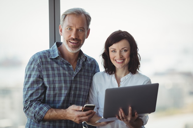 Portrait of business executives using mobile phone and laptop