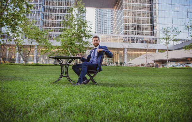 Portrait of business man sitting on modern outdoor working place Successful business Background of terrace in modern business centre