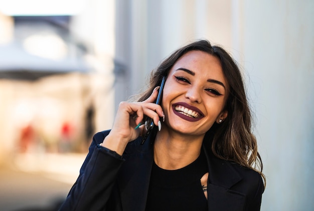 Portrait of business woman outdoors with cellphone. Close-up of brunette girl