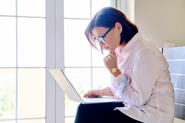 Portrait of a business woman working with a laptop sitting on a chair in the office