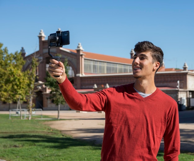 Portrait of businessman recording video presentation at smartphone with steadycam. Focused young man