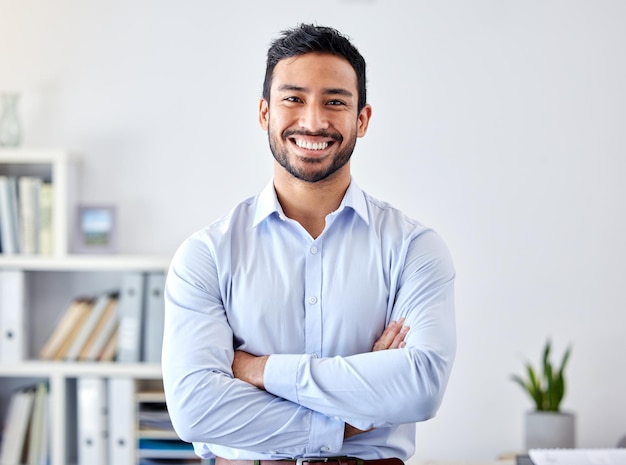 Portrait of a businessman with a smile in a corporate modern office of a startup company Happy career and professional manager or entrepreneur standing with his arms crossed in his workspace