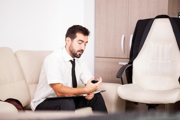 Portrait of Businessman working in the office on the couch putting long hours of work. Businessperson in professional environment