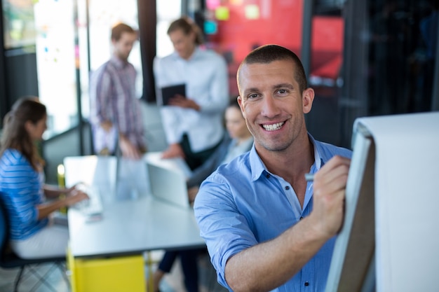 Portrait of businessman writing on flip chart