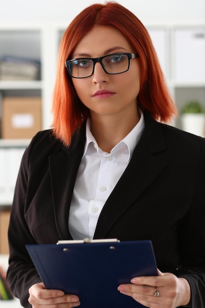 Portrait of businesswoman in glasses in business suit with clipboard