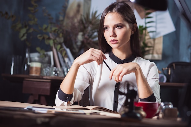 Portrait of a businesswoman who is working at office and checking details of her upcoming meeting in her notebook and working at loft studio