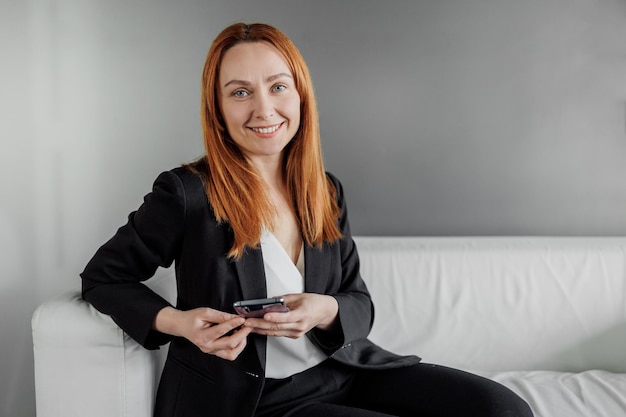 Portrait of a businesswoman with her phone administrating a business from home