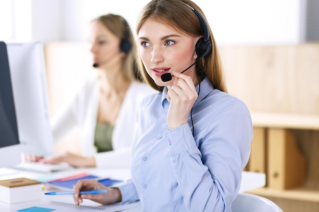 Portrait of call center operator at work. Group of people in a headset ready to help customers. Business concept.