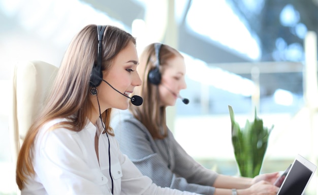 Portrait of call center worker accompanied by her team. Smiling customer support operator at work.