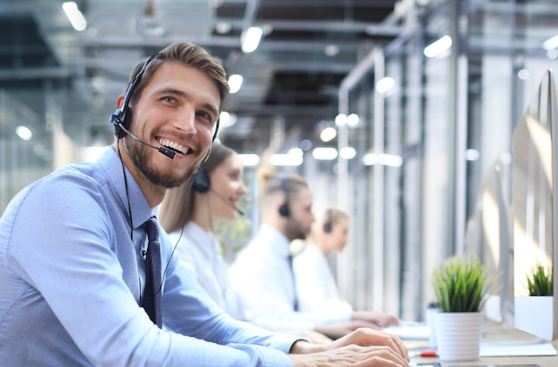 Portrait of call center worker accompanied by his team Smiling customer support operator at work