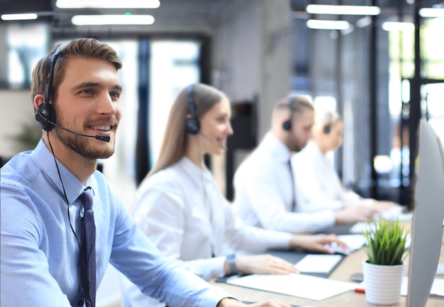 Portrait of call center worker accompanied by his team Smiling customer support operator at work