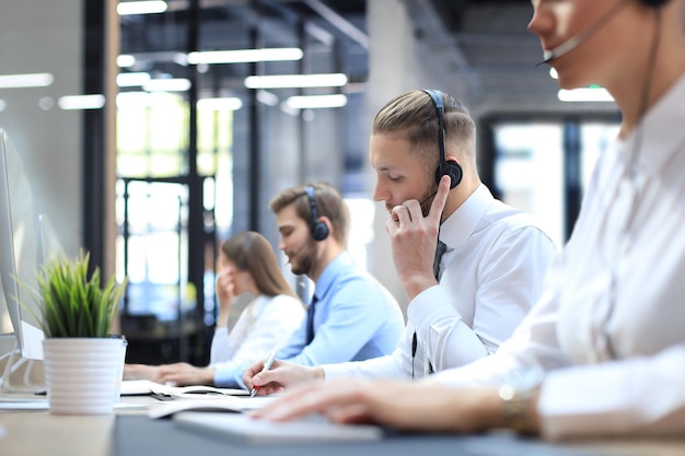 Portrait of call center worker accompanied by his team Smiling customer support operator at work