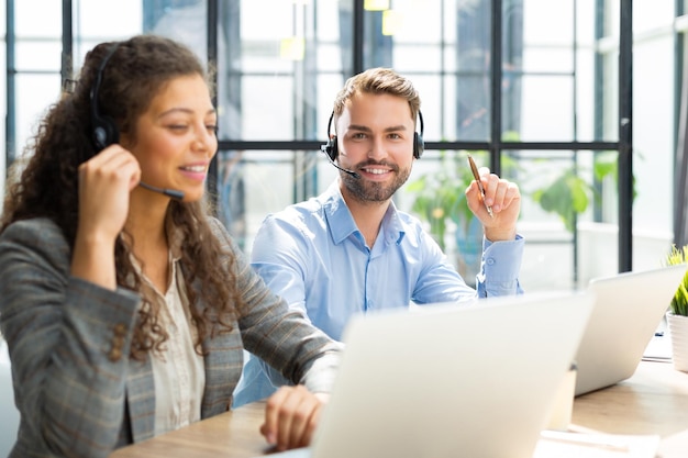 Portrait of call center worker accompanied by his team Smiling customer support operator at work