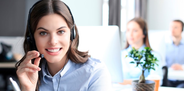 Portrait of call center worker accompanied by his team. Smiling customer support operator at work.