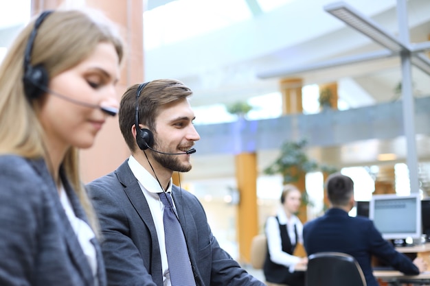 Photo portrait of call center worker accompanied by his team. smiling customer support operator at work.