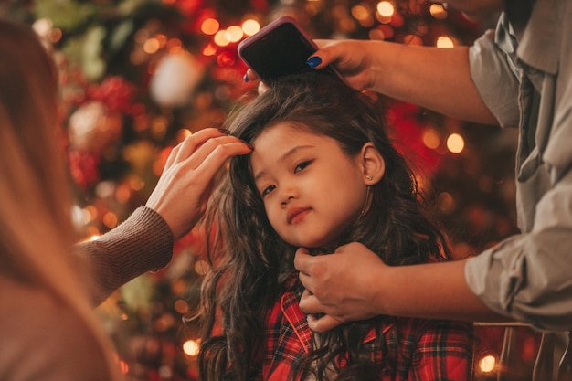 Portrait of candid authentic asian dreamer little girl in red plaid pajama waiting Santa at Xmas