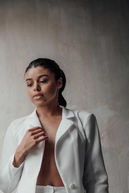 Portrait of candid authentic elegant sexy mixed race model girl posing in white pantsuit with bra