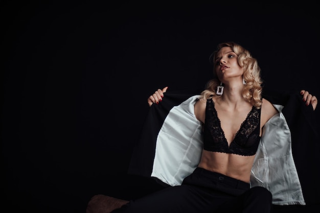 Portrait of candid authentic elegant sexy model blonde girl posing in black pantsuit with bra