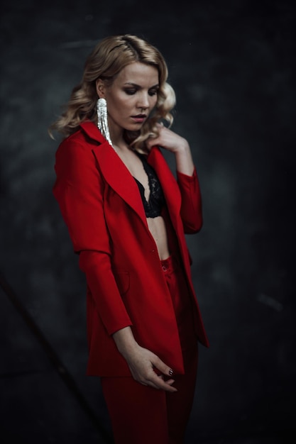 Portrait of candid authentic elegant sexy model blonde girl posing in bra and red pantsuit at studio