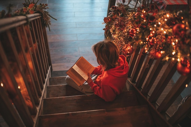 Portrait of candid authentic smiling boy teenager reading book on distance studying at home Xmas