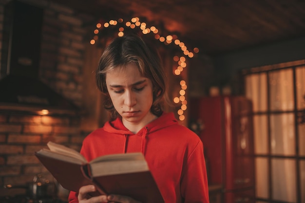 Portrait of candid authentic smiling boy teenager reading book on distance studying at home Xmas