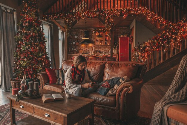 Portrait of candid authentic smiling handsome boy teenager using mobile phone at Xmas home interior