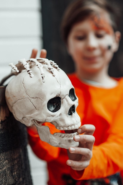 Portrait of candid authentic teen boy with face painted at decorated skeletons party Halloween