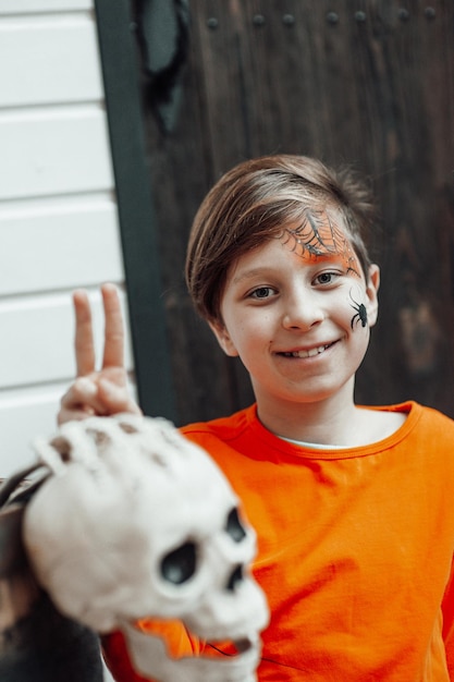 Portrait of candid authentic teen boy with face painted at decorated skeletons party Halloween