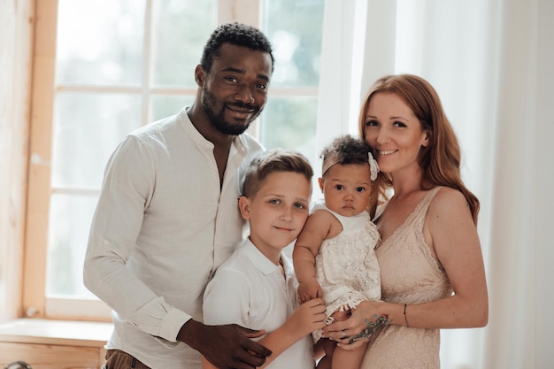 Portrait of candid friendly happy interracial family with two kids spending time together at home